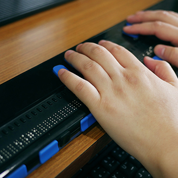 Individual using a braille keyboard representing how FAAST increases the public awareness of available assistive technology
